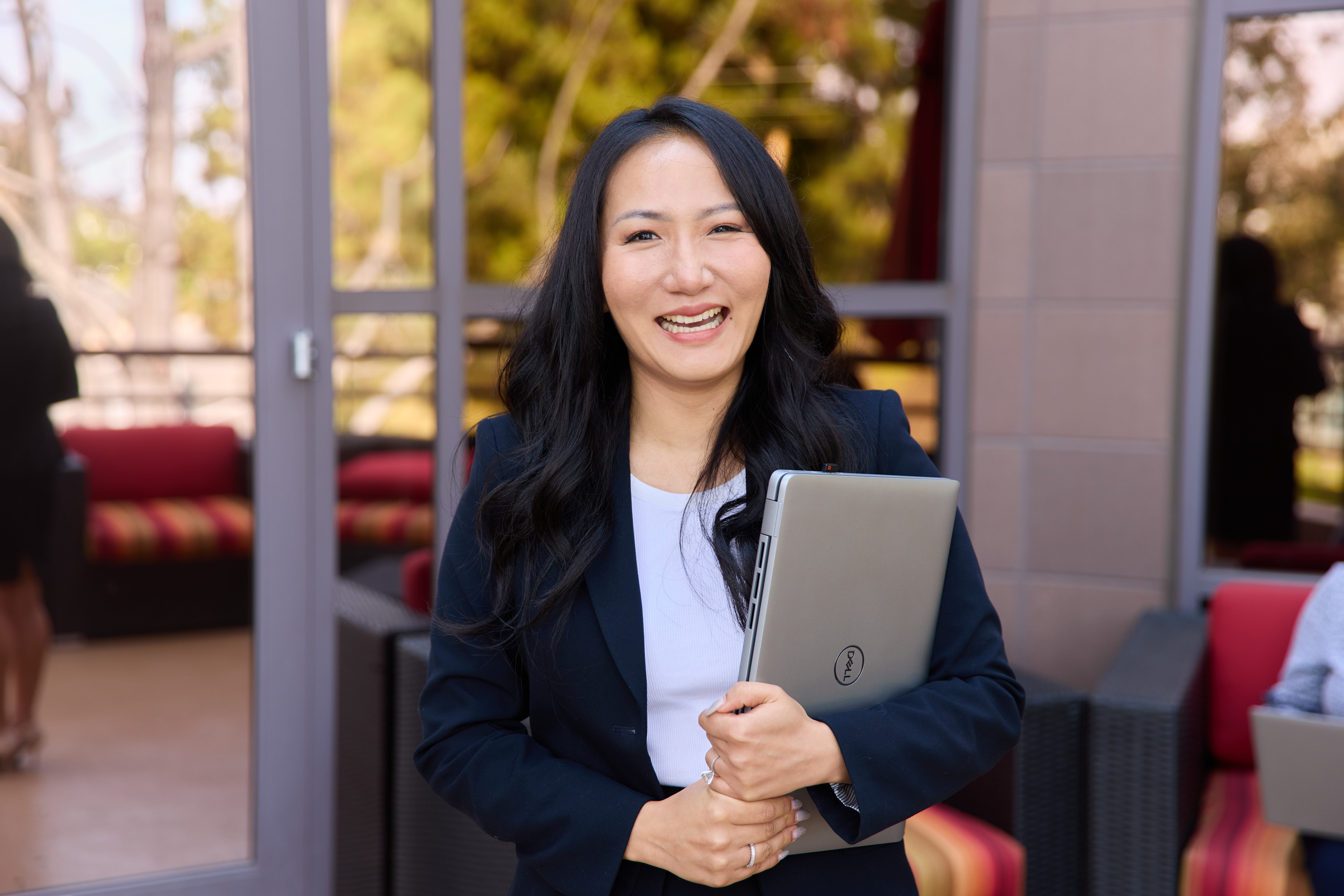 A woman smiles while holding a laptop.