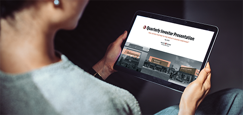 A person holding a tablet device displaying the investor presentation. 