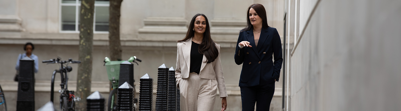 Two female colleagues walking down a street.
